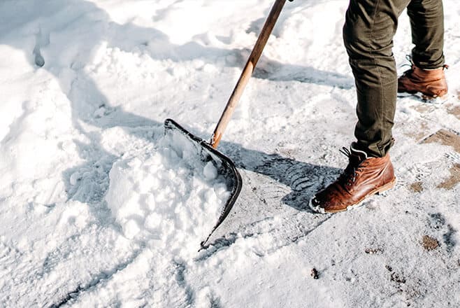 Mann schaufelt Schnee mit Schaufel